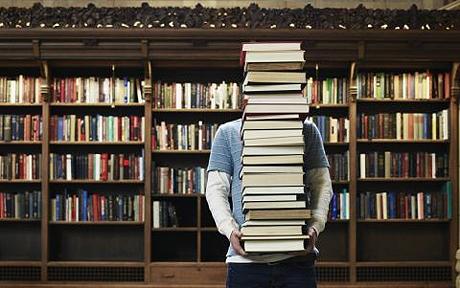 person hidden by stack of books
